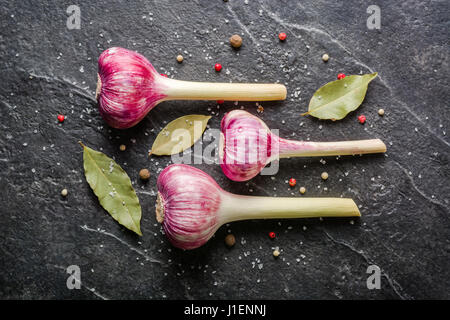 Garlic purple with stem on a black stone background. A lot of empty space. Stock Photo