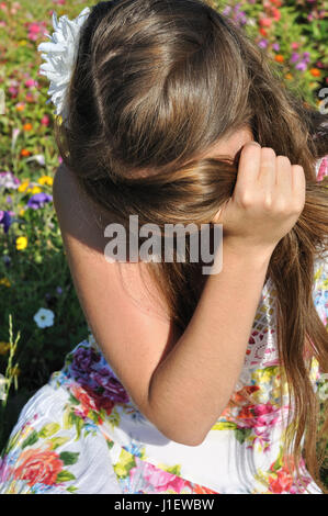young lonely woman sitting on grass at the meadow in summer day Stock Photo