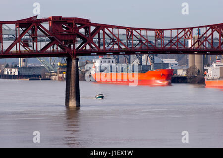 Red adjustable lifting iron truss bridge Rose Portland Willamette River through which float on large and small ships and boats on the background Stock Photo