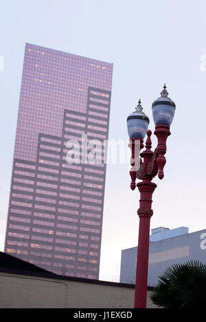 Lamppost with two glass lanterns patterned shapes against high contemporary skyscraper with pink colored glass, as a combination of the two cultures Stock Photo