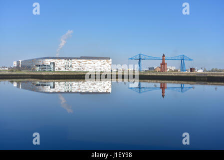 The Transporter Bridge, Middlesbrough, and the Sixth-form college seen reflected in the docks section of the River Tees Stock Photo