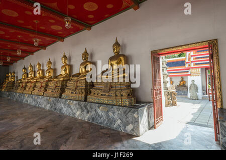 Several golden statues of sitting Buddha and an open door to a courtyard at the Wat Pho (Po) temple complex in Bangkok, Thailand. Stock Photo