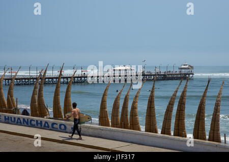 Historic iron pier 108 metres in length at Huanchaco on the coast of Peru. Constructed in around 1891. Traditional fishing boats in the foreground. Stock Photo