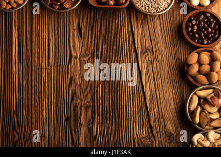 Different nuts in bowls on wooden table. Chocolate. Stock Photo