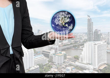 Target audience and customers concept. Young businesswoman holding globe target customers in hand over cityscape background. Elements of this Image Fu Stock Photo