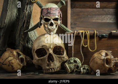 closeup pirate skull with two swords over on human skull pile awesome and treasure coffer background still life style, pirate concept for halloween Stock Photo