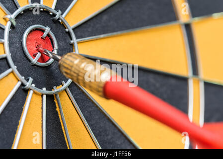 closeup red dart arrow hitting in target bullseye of dartboard, business solutions and success concept Stock Photo