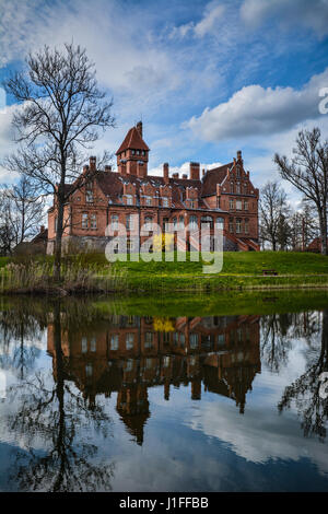 Jaunmoku castle near Tukums, Latvia reflecting in the lake. Beautiful blue sky and scenic clouds in the background on a sunny day. Postcard view. Stock Photo
