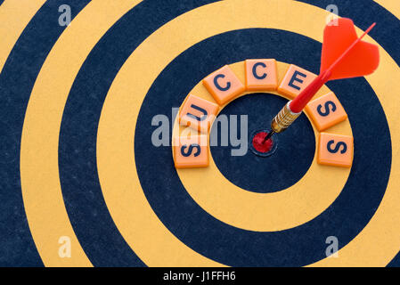 Dart hitting the bullseye target with word success on dartboard, Success business finance investment concept, symbol of successful Stock Photo