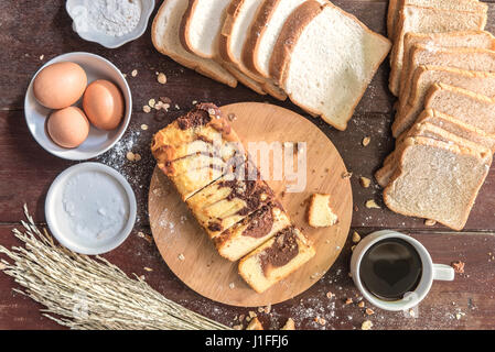 Love of Coffee cup and chocolate marble cake on cutting board with bread and ingredient in kitchen Stock Photo