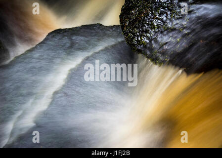 Close up of water flowing over rocks in a long exposure. Stock Photo