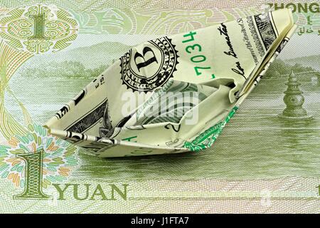 US Dollar paper boat on Chinese 1 Yuan note Stock Photo