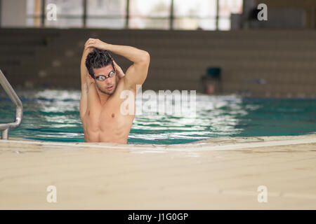 swimmer in pool water, stretching arms, indoors. Stock Photo