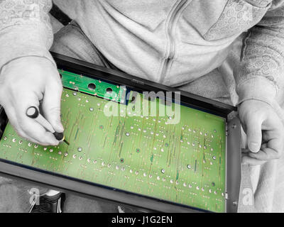 Man repairing a computer mother board on the knees, selective color closeup, concept of DIY repair Stock Photo