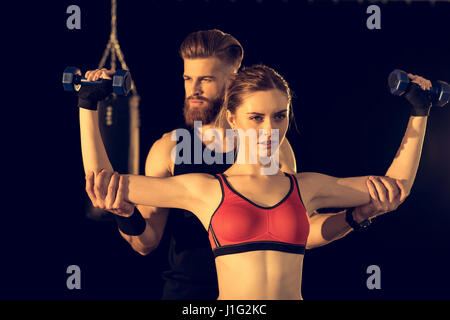 Bearded handsome man training young sporty woman with dumbbells Stock Photo