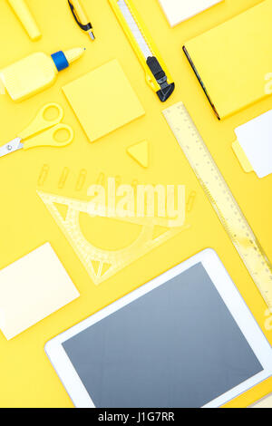 Top view of digital tablet with blank screen and office supplies on yellow tabletop Stock Photo