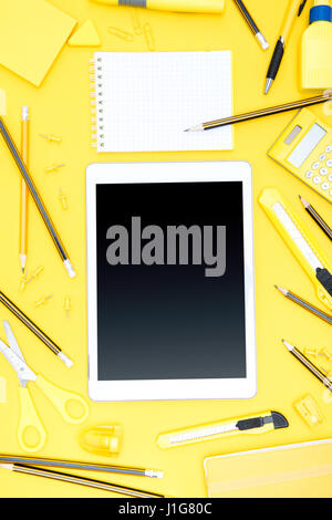 Flat lay of office supplies, digital tablet, notepad and pencils on yellow Stock Photo