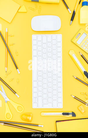 Flat lay of office supplies, keyboard and computer mouse on yellow Stock Photo