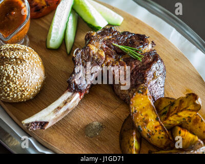 Grilled Steak on bone Veal rib with baked potatoes and vegetables on a wooden cutting board Stock Photo