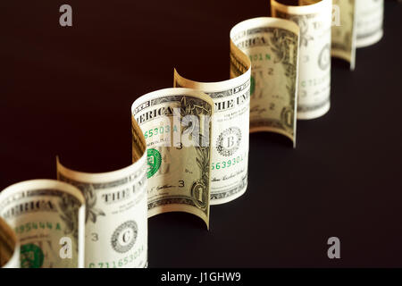Few one dollar bank notes curved as sign on dark background Stock Photo