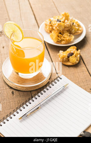 Notebooks with snacks and orange juice on a wooden table background Stock Photo