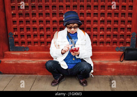 An elderly woman using a smartphone in Japan. Stock Photo