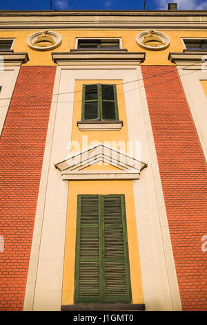 Red brick wall and green wooden window shutter details on a colourful Italian style architectural building facade,Tirana, Albania, Eastern Europe Stock Photo