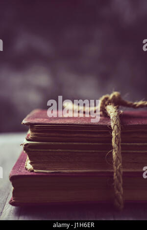 a pile of old books tied with a jute string on a rustic wooden table Stock Photo