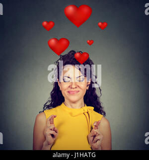 Young woman in love making a wish keeps her fingers crossed isolated on gray background Stock Photo