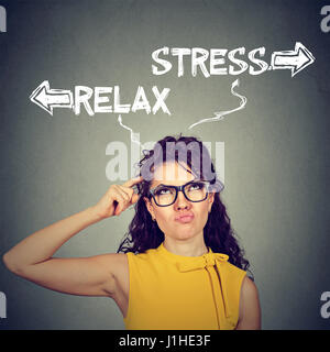 Stress or relax. Portrait confused skeptical young woman thinking looking up isolated on gray wall background. Human face expressions, emotions, feeli Stock Photo