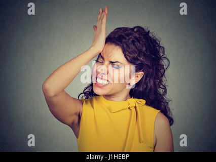 Regrets wrong doing. Silly young woman, slapping hand on head having duh moment isolated on gray background. Negative human emotion facial expression  Stock Photo