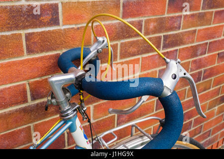 Bicycle with padded classic drop handlebars leaning up against a brick wall. UK Stock Photo