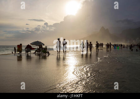 RIO DE JANEIRO - JANUARY 16, 2017: Beachgoers walk along the shore of Ipanema Beach as dark clouds threaten the sunset on a summer afternoon. Stock Photo