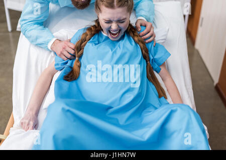 pregnant woman giving birth in hospital while man hugging her Stock Photo