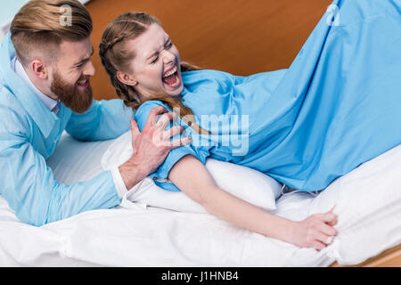 pregnant woman giving birth in hospital while man hugging her Stock Photo