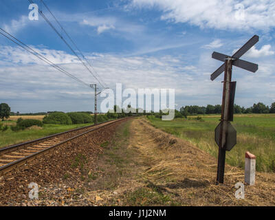 Karpiska, Poland - June 28, 2016: View over railroad tracks and meadow by a railway crossing Stock Photo