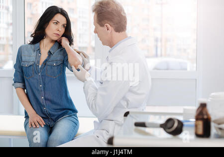 Mature doctor examining skin of the patient in the clinic Stock Photo