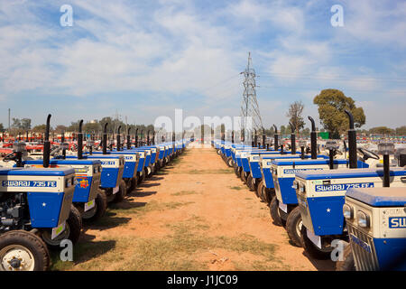 rows of brand new tractors at a factory in chandigarh punjab india under a blue cloudy sky Stock Photo