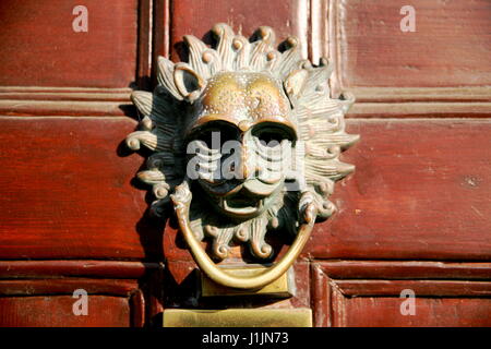 A brass sun door knocker on a wooden door Stock Photo
