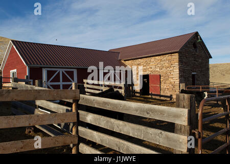 Corral provides foreground for old stone barn. Scarlet red and white trimmed frame addition doubles capacity of classic stone structure. Stock Photo