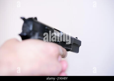 Pistol in hands on a man on light background Stock Photo