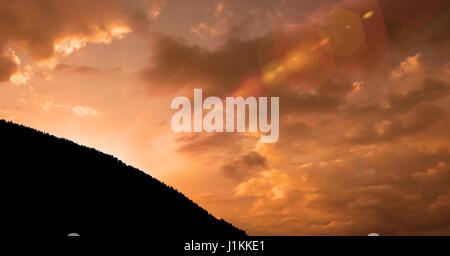 Digital composite of Silhouette mountain against cloudy sky during sunset Stock Photo