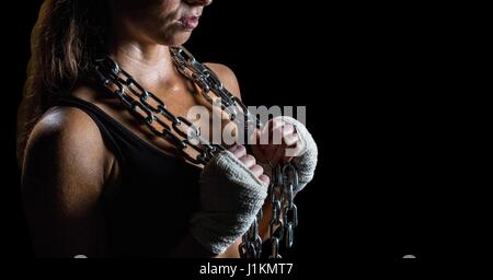 Digital composite of Woman with chains against black background Stock Photo