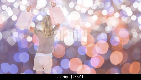 Digital composite of Happy female with shopping bags over bokeh Stock Photo