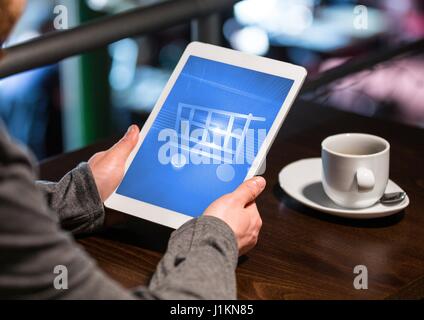 Digital composite of Person using Tablet with Shopping trolley icon and coffee Stock Photo