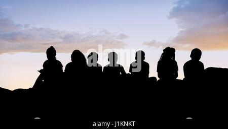 Digital composite of Silhouette kids sitting on hill against sky Stock Photo