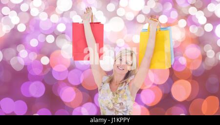 Digital composite of Happy woman with arms raised carrying shopping bags over bokeh Stock Photo