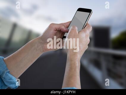 Digital composite of Hands with phone against blurry bridge Stock Photo