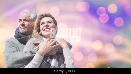 Digital composite of Happy couple in warm clothing against bokeh Stock Photo