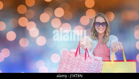 Digital composite of Happy woman showing shopping bags over bokeh Stock Photo